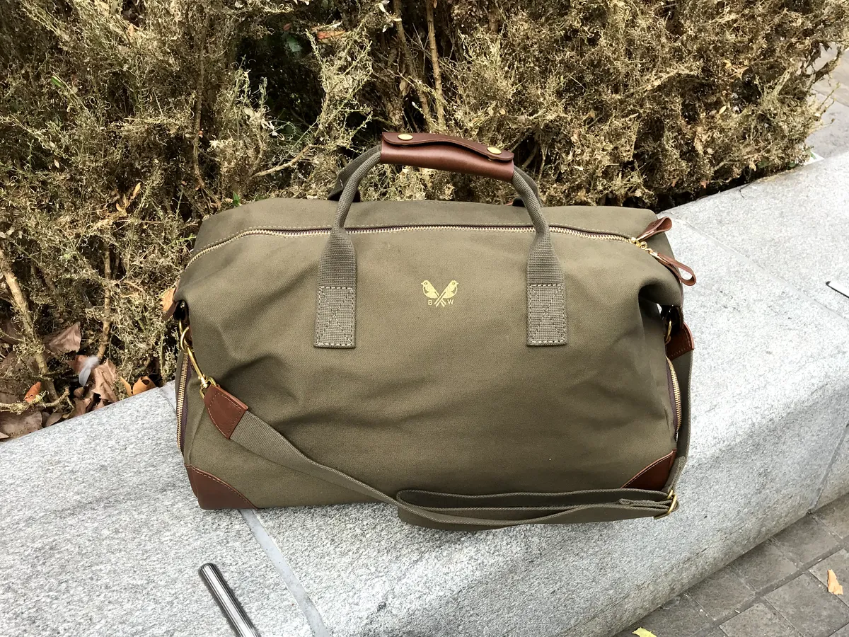 Bennett Winch Olive Green Canvas Weekender on a stone bench