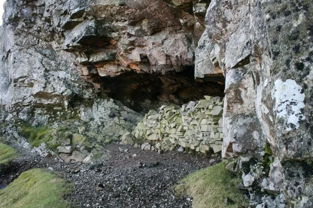 Priests Hole Cave with stone wall and crag