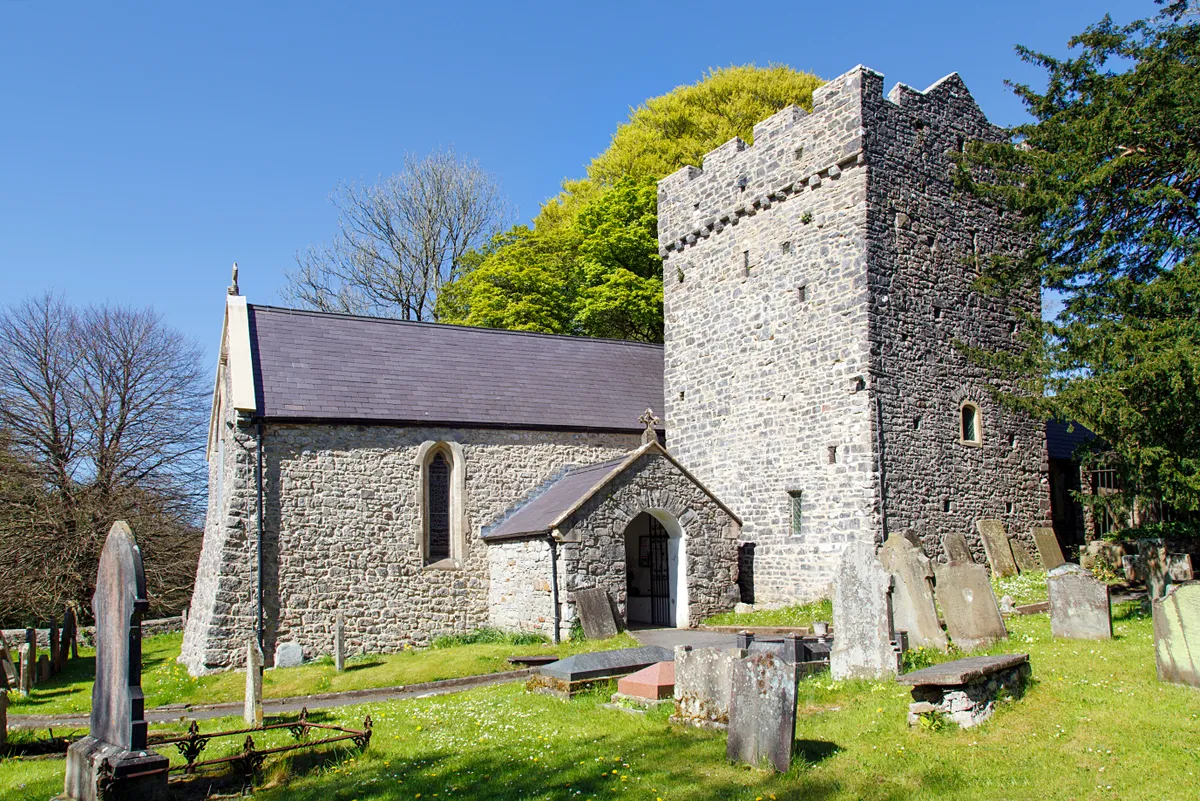 St Illtyd's Church in Ilston on the Gower Peninsular with trees and blue sky