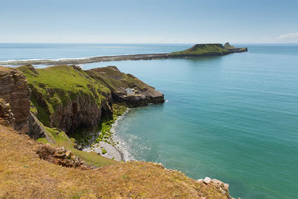 Worms Head and Rhossili Bay on the Gower peninsula on a sunny day with sea and blue sky