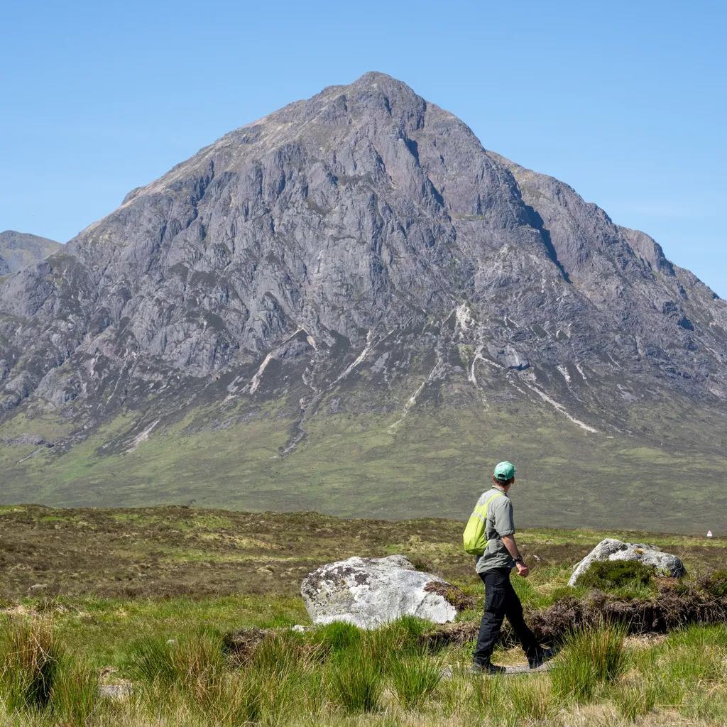 Walker on the West Highland Way with blue sky and mountains