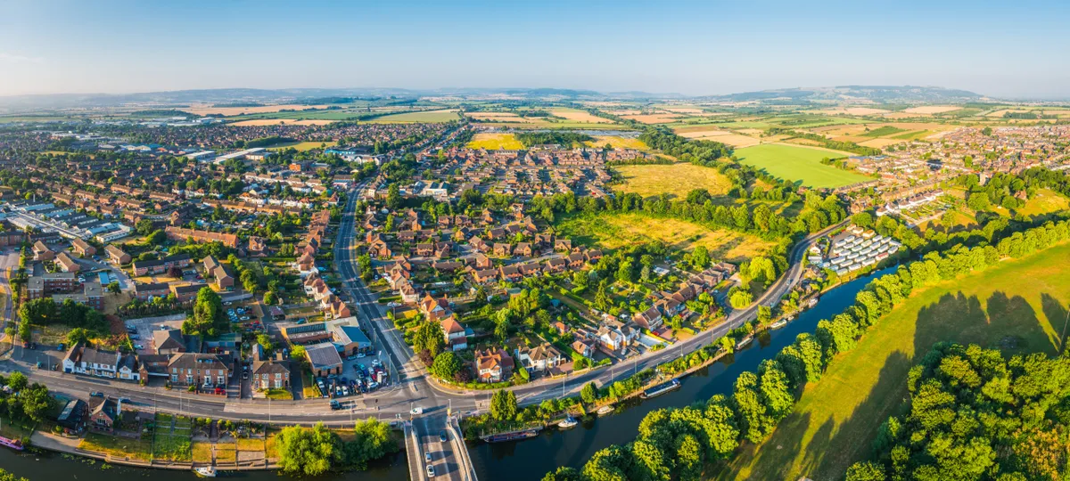 Aerial panorama over suburban family homes surrounded by green fields and waterways