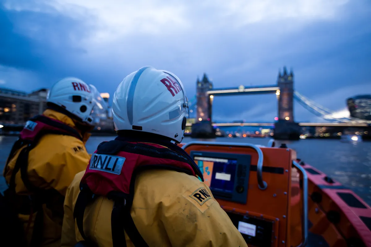 Three lifeboat crew on board heading out for a training exercise on the Thames
