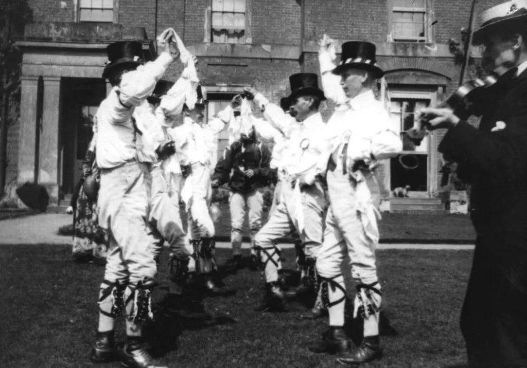Male Morris dancers dancing in a row in a black and white image from 1906