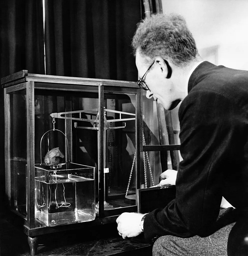 Dr. Max H. Hey of London's Natural History Museum weighing  the Beddgelert meteorite, by using a balance scale and container of water to discover it's weight and relative density. Photo by Hulton-Deutsch/Hulton-Deutsch Collection/Corbis via Getty Images