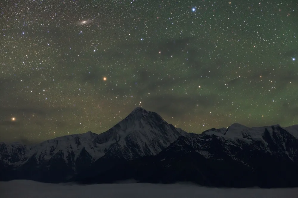 The stars of constellation Andromeda and, look for the smudge top right to see the magnificent Andromeda Galaxy rise above the highest peak of Mount Gongga, Sichuan province, China. Credit: Jeff Dai