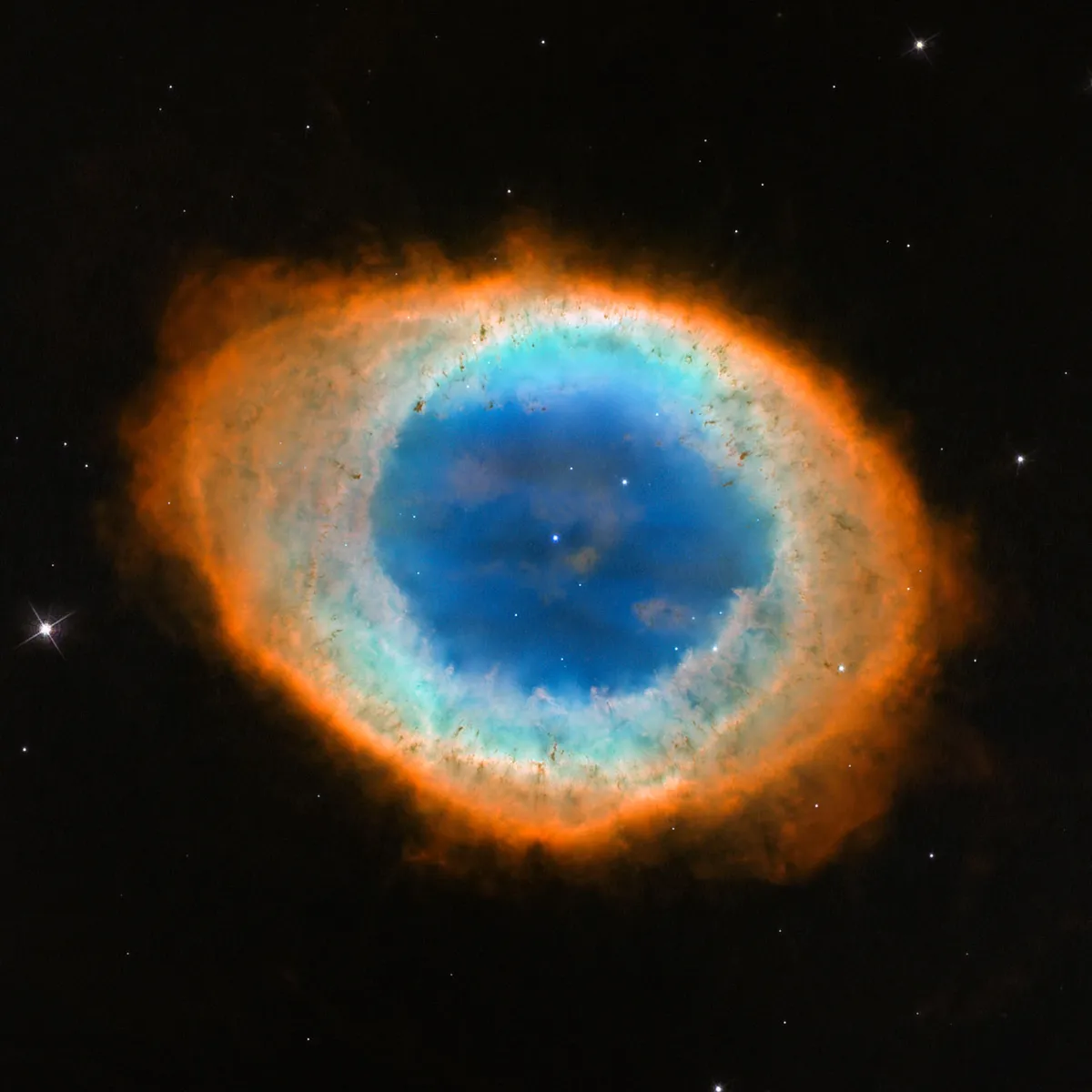 This new image shows the dramatic shape and colour of the Ring Nebula, otherwise known as Messier 57. From Earth’s perspective, the nebula looks like a simple elliptical shape with a shaggy boundary. However, new observations combining existing ground-based data with new NASA/ESA Hubble Space Telescope data show that the nebula is shaped like a distorted doughnut. This doughnut has a rugby-ball-shaped region of lower-density material slotted into in its central “gap”, stretching towards and away from us.
