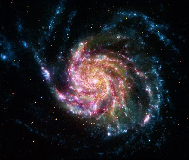 This image of the Pinwheel Galaxy, or M101, combines data in the infrared, visible, ultraviolet and x-rays from four of NASA’s space telescopes. This multi-spectral view shows that both young and old stars are evenly distributed along M101’s tightly-wound spiral arms. Such composite images allow astronomers to see how features in one part of the spectrum match up with those seen in other parts. It is like seeing with a regular camera, an ultraviolet camera, night-vision goggles and X-Ray vision, all at once! The Pinwheel Galaxy is in the constellation of Ursa Major (also known as the Big Dipper). It is about 70% larger than our own Milky Way Galaxy, with a diameter of about 170,000 light years, and sits at a distance of 21 million light years from Earth. The red colors in the image show infrared light, as seen by the Spitzer Space Telescope. These areas show the heat emitted by dusty lanes in the galaxy, where stars are forming. The yellow component is visible light, observed by the Hubble Space Telescope. Most of this light comes from stars, and they trace the same spiral structure as the dust lanes seen in the infrared. The blue areas are ultraviolet light, given out by hot, young stars that formed about 1 million years ago. The Galaxy Evolution Explorer (GALEX) captured this component of the image. Finally, the hottest areas are shown in purple, where the Chandra X-ray observatory observed the X-ray emission from exploded stars, million-degree gas, and material colliding around black holes. Credit: NASA/JPL