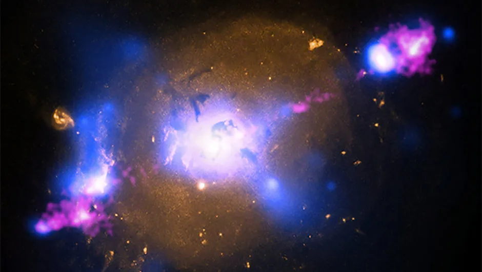 An image of 4C 29.30, a galaxy 850 million lightyears away. X-ray data from NASA's Chandra X-ray Observatory is seen in blue, optical light obtained from Hubble Space Telescope is gold and radio waves from the NSF's Very Large Array are pink. The radio emission comes from jets of particles speeding at millions of miles per hour away from a supermassive black hole at the center of the galaxy. Credit: NASA