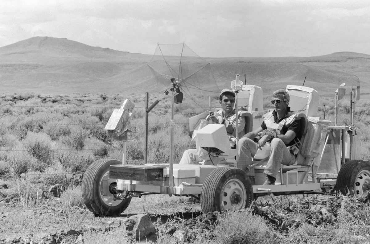 Test drive,6 September 1972. Apollo 17 Commander Eugene A Cernan (foreground) and Lunar Module pilot Harrison H Schmitt (on Cernan's right) take the Lunar Roving Vehicle trainer for a spin in the Pancake Range area of south-central Nevada.Credit: NASA