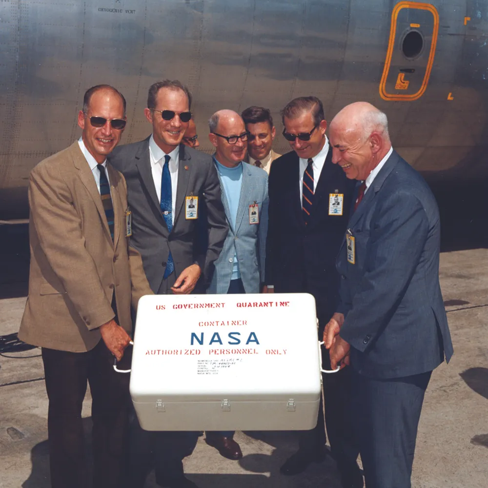 25 July 1969. NASA scientists are delighted to take charge of the first of Apollo 11’s sample return containers full of lunar rocks, after it arrives by air at Ellington Air Force Base near Houston. Credit: NASA