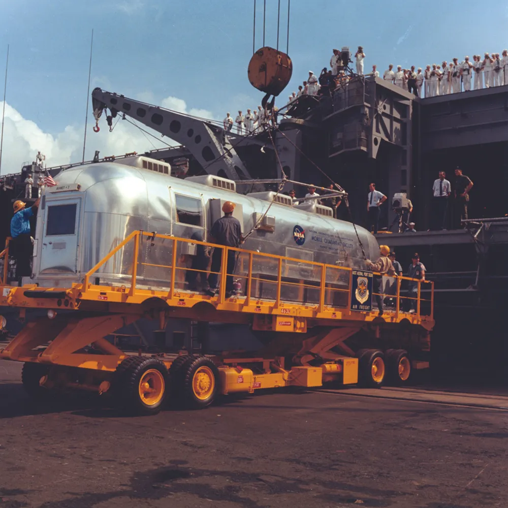 26 July 1969. When it arrives in Hawaii, the mobile quarantine facility still containing the crew is off-loaded from the USS Hornet ready for its flight back to Houston. Credit: NASA