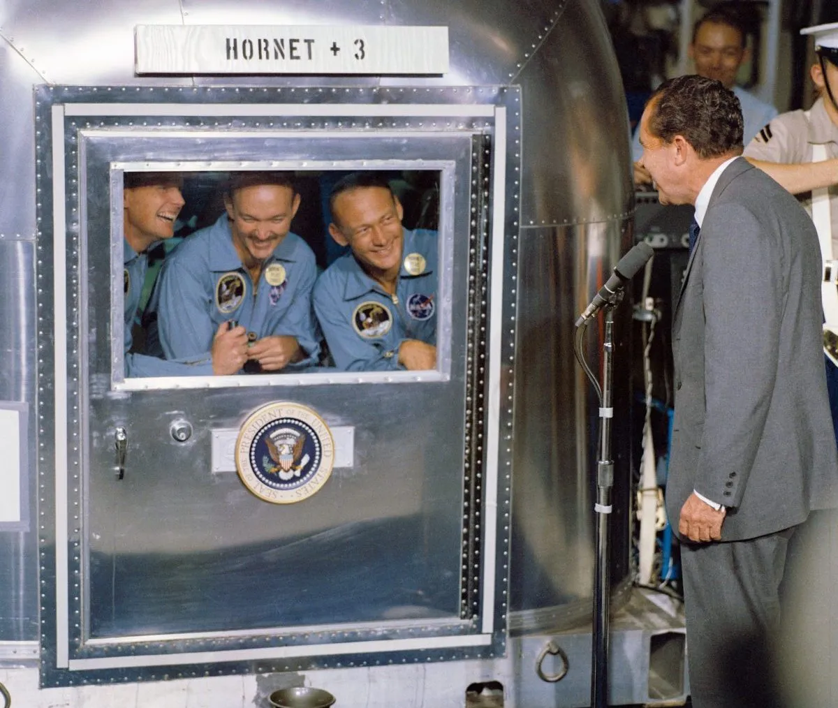 US President Richard Nixon welcomes the Apollo 11 astronauts back to Earth, aboard the USS Hornet. Here, Neil Armstrong, Michael Collins and Buzz Aldrin greet the President from the confines of their quarantine facility. Credit: NASA