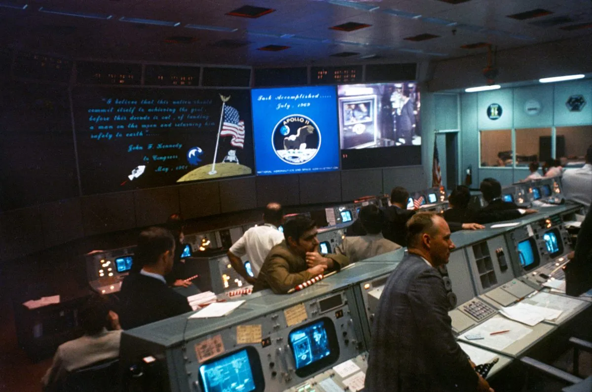 Mission Control during Apollo 11. On the monitors can be seen the mission patch, a quote by JFK and President Richard Nixon greeting the astronauts. Credit: NASA