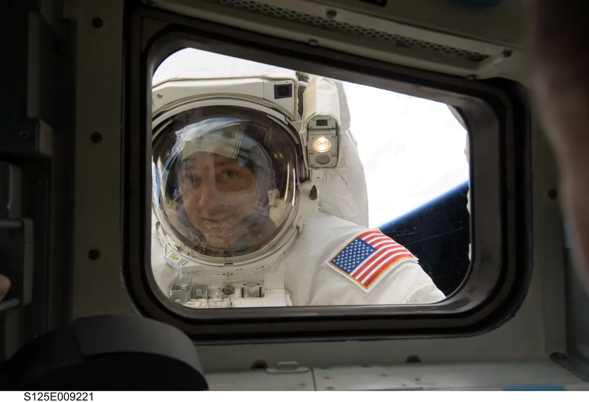 Astronaut Mike Massimino peers through the window of Atlantis during mission STS-125, May 2009. This was the last mission to service the Hubble Space Telescope. Credit: NASA