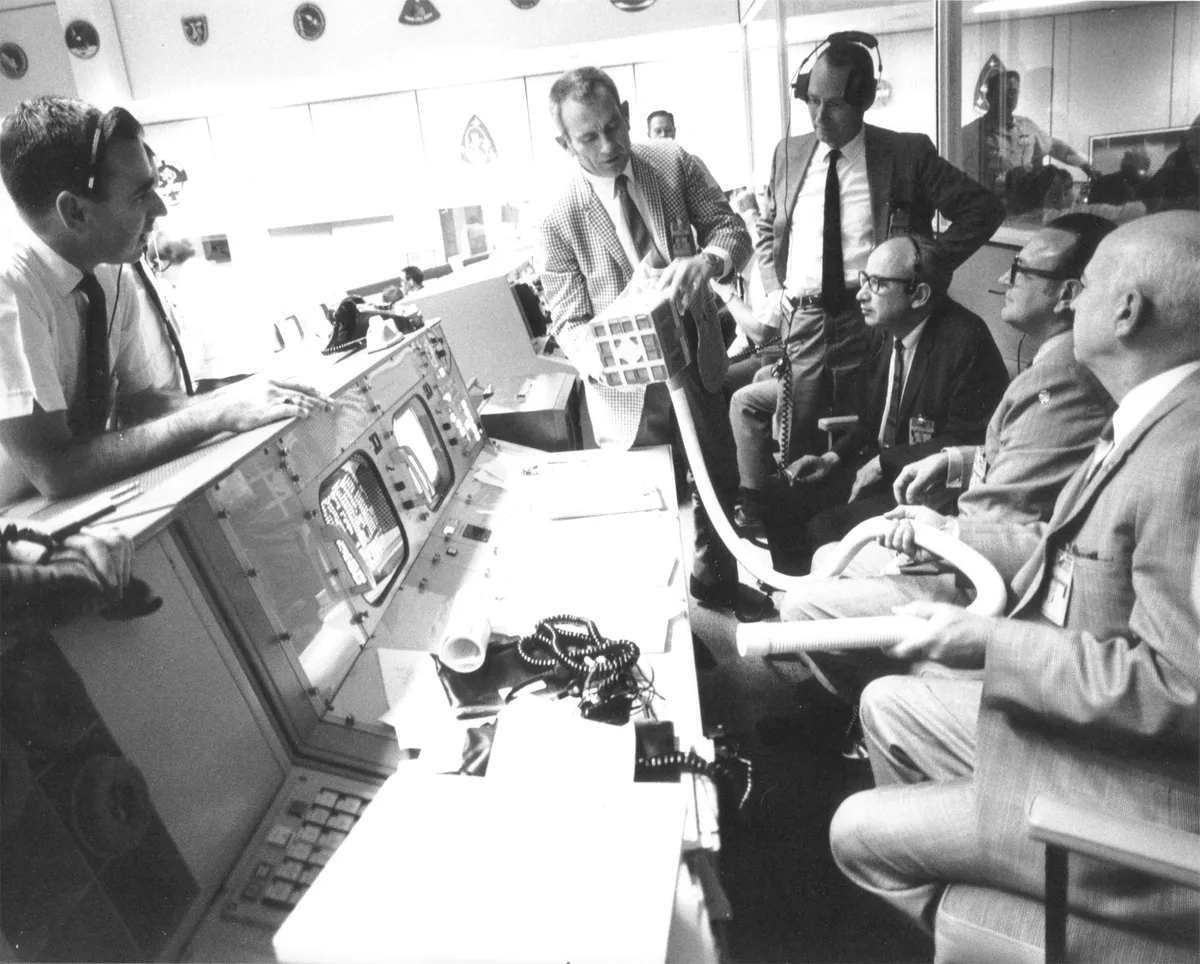 NASA’s Deke Slayton examines the makeshift adaptor to reduce CO2 levels, before instructions are relayed to the Apollo 13 crew. Credit: NASA