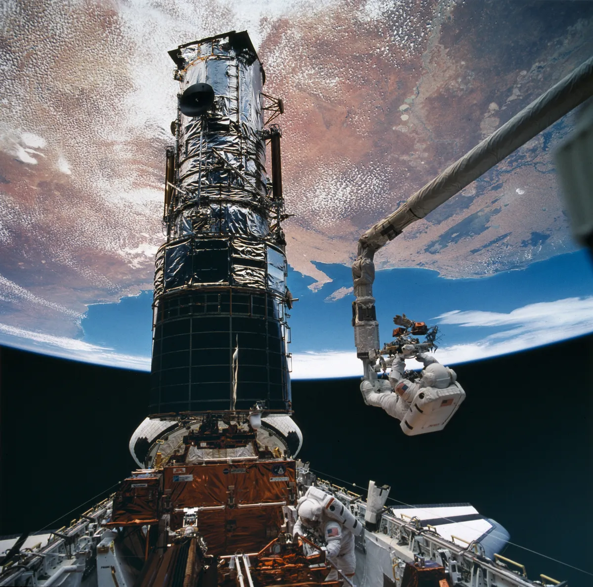Astronaut Story Musgrave prepares to be elevated to the top of Hubble to install protective covers on its pointing control system, during the mission to repair Hubble. Credit: NASA