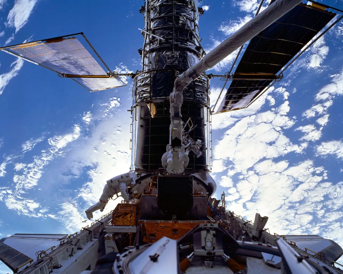 Astronauts C. Michael Foale, left, and Claude Nicollier install a Fine Guidance Sensor (FGS) onto the Hubble Space Telescope while in the payload bay of Space Shuttle Discovery. Their spacewalk lasted from 19:06 UTC on 23 December until 03:16 UTC on 24 December. Credit: NASA/ESA