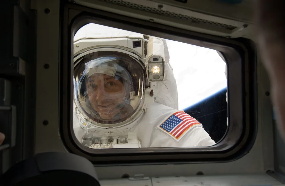 Mike Massimino peers through the Shuttle’s aft flight deck window during the mission’s fourth spacewalk. Credit: NASA