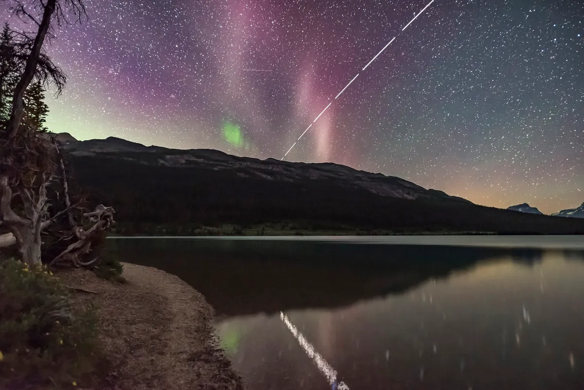The International Space Station appears in the night sky above Banff National Park, Canada. Also visible in the image is the auroral phenomenon known as STEVE. Credit: Alan Dyer/Stocktrek Images/Getty Images