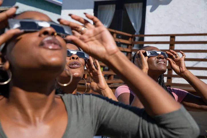 Women observing a solar eclipse safely with eclipse glasses. Credit: Leo Patrizi / Getty