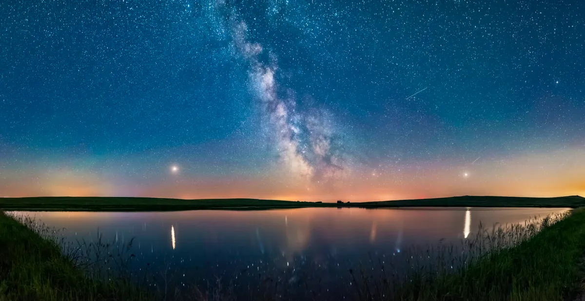 A panorama showing the Milky Way (centre) and planets. Mars is bright to the left, Saturn is dimmer and bright Jupiter is right. The arcing line joining the planets defines the arc of the ecliptic. Credit: Alan Dyer / Stocktrek Images / Getty Images