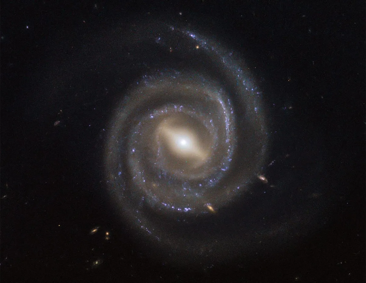 La galaxie spirale barrée UGC 6093 est une galaxie active, c'est-à-dire qu'elle contient un noyau galactique actif.  La matière est attirée vers le trou noir supermassif central, le chauffant et faisant briller le noyau de la galaxie.  Crédit : ESA/Hubble