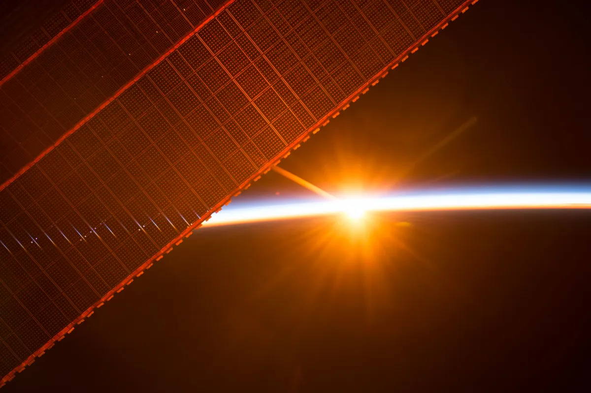 The rising Sun shines through the solar arrays of the International Space Station. Credit: NASA