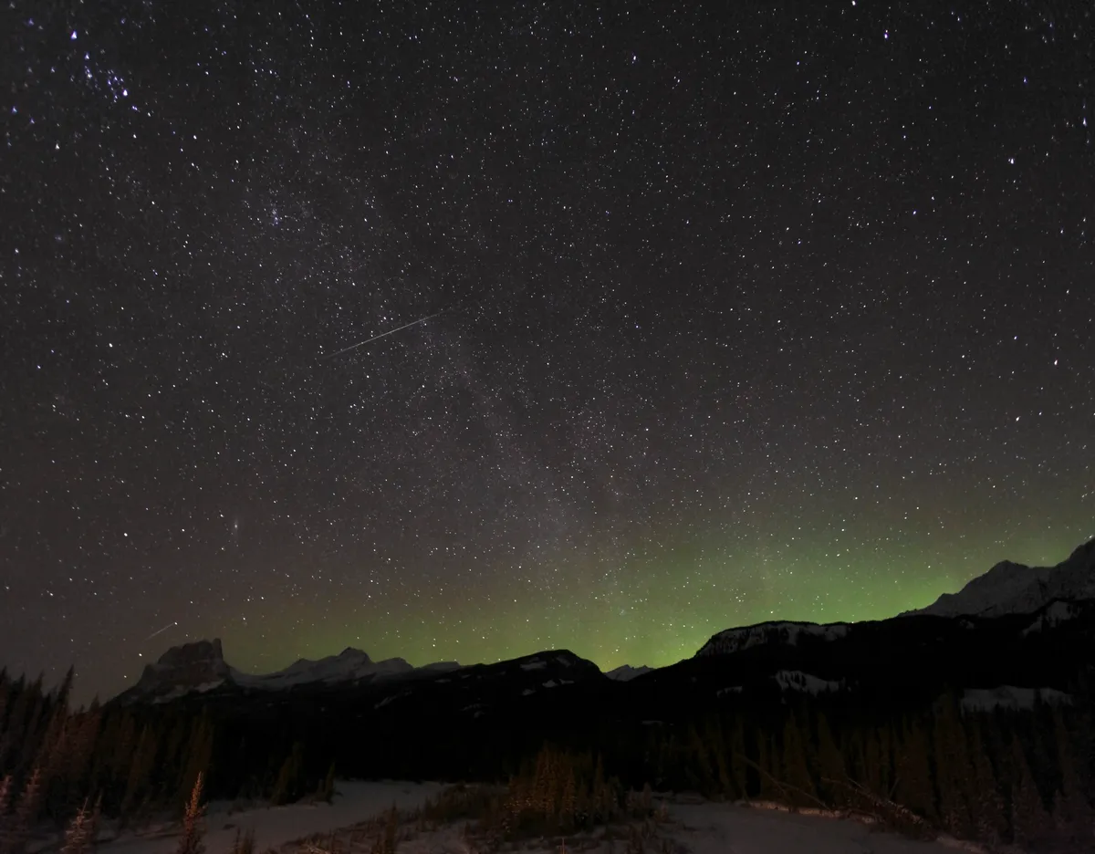 A Quadrantid meteor appears in the night sky along with the Milky Way and the Aurora over Banff National Park, Canada, 3 January 2009. Credit: Stocktrek Images / Getty Images