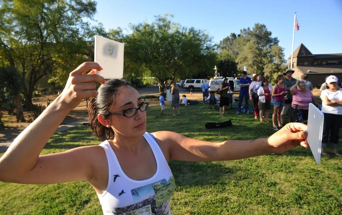 A woman projects a pinhole image of a solar eclipse through a piece of tin foil on to paper, California, 20 May 20 2012. Credit: John Walker/Fresno Bee/Tribune News Service via Getty Images.
