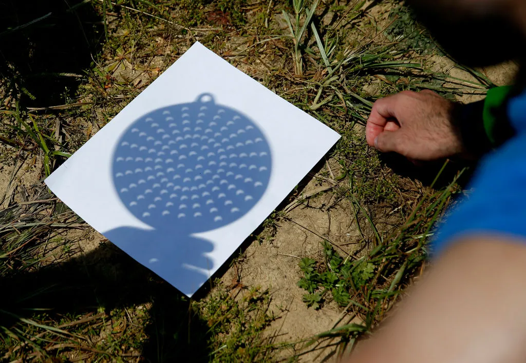 A regular kitchen colander can be used to project an eclipse onto a piece of white paper or card. Photo by Jessica Rinaldi/The Boston Globe via Getty Images