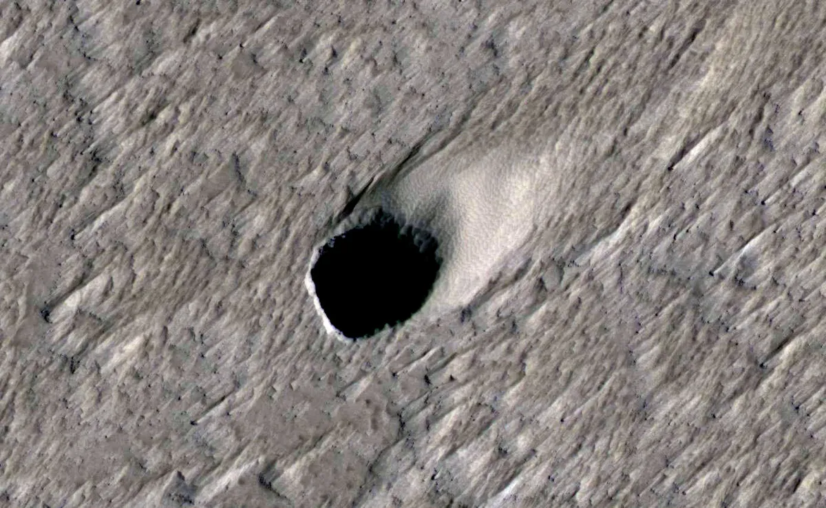 A pit crater on Arsia Mons, imaged by the Mars Reconnaissance Orbiter. The crater was created when an empty underground lava tube collapsed. Credit: NASA/JPL-Caltech/University of Arizona
