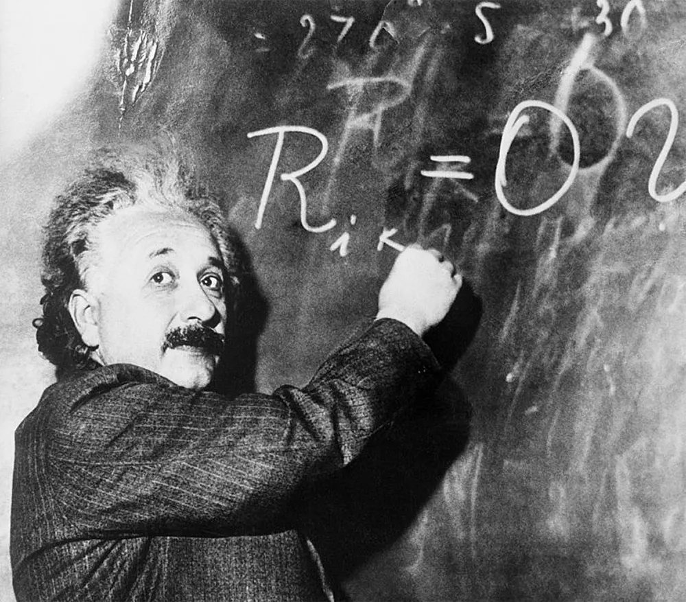 Albert Einstein writing an equation on a chalkboard