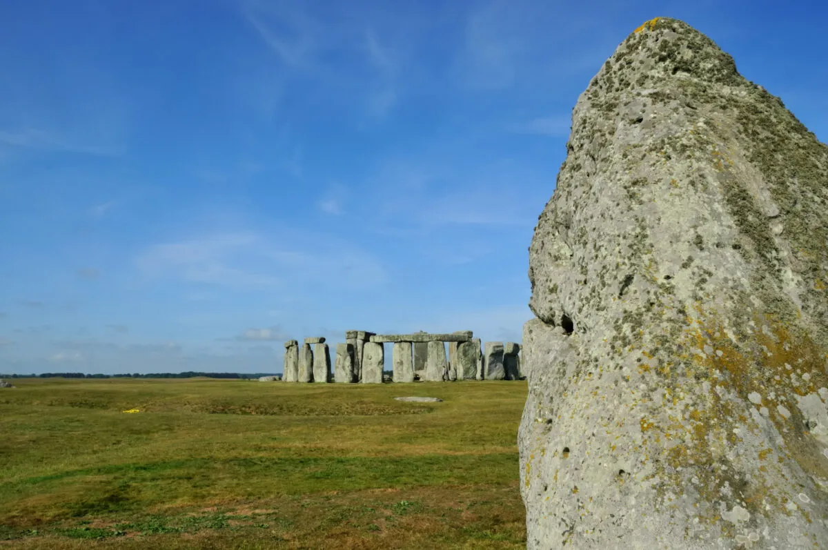 The heal stone with the rest of Stonehenge in the background and behind that Salisbury Plain at the summer solstice
