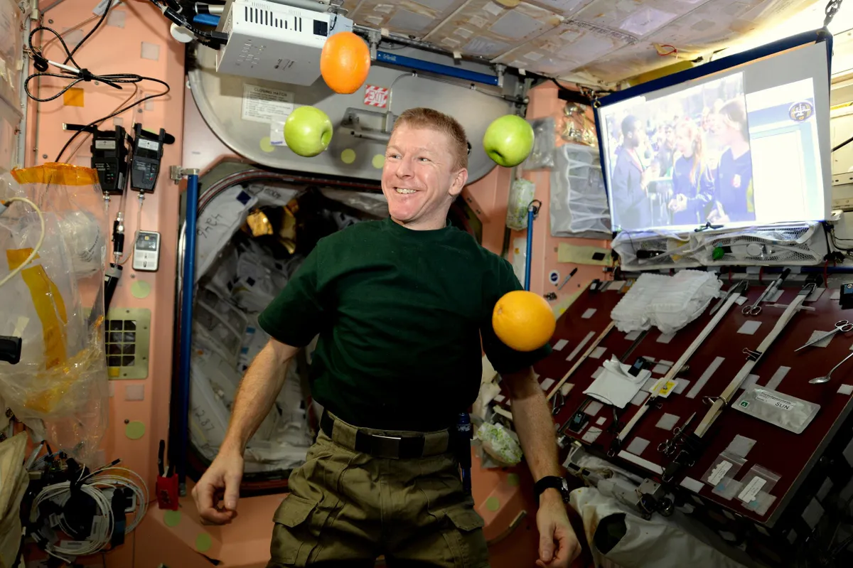 Astronaut Tim Peak floats on the ISS surrounded by fresh apples and oranges