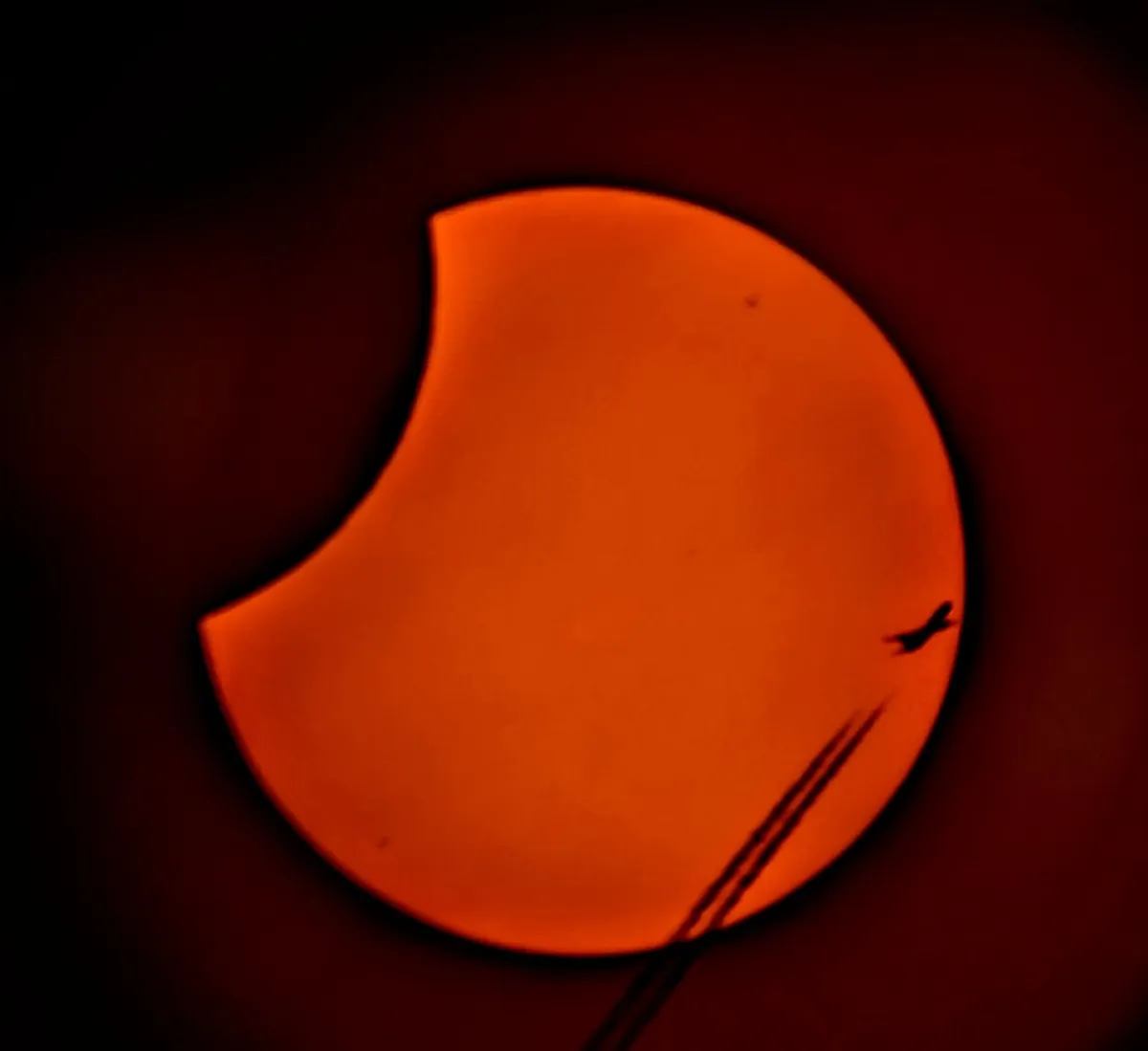 Partial Solar Eclipse and a plane, captured by Sonia Turkington, North Reddish, Stockport, UK, 25 October 2022, using a Sky-Watcher 10-inch Dobsonian a Google Pixel smartphone and Seymour 12” solar film.