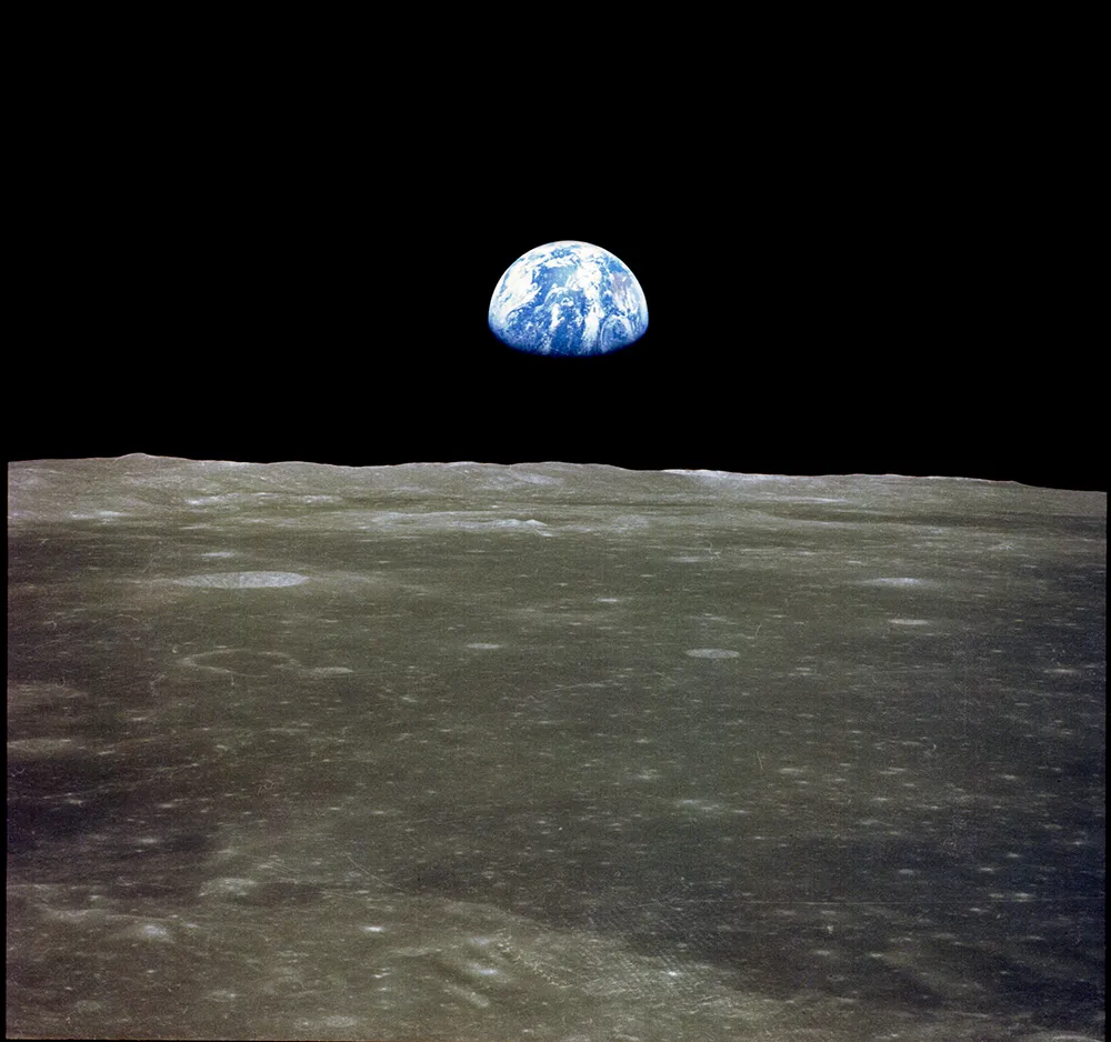 A half illuminated Earth appears over the edge of the Moon.