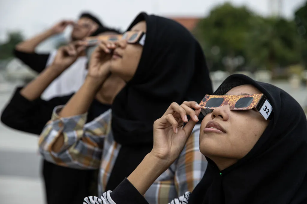 Eclipse chasers in Surabaya , Indonesia observe a hybrid solar eclipse wearing solar eclipse glasses on 20 April 2023. Photo by Robertus Pudyanto/Getty Images