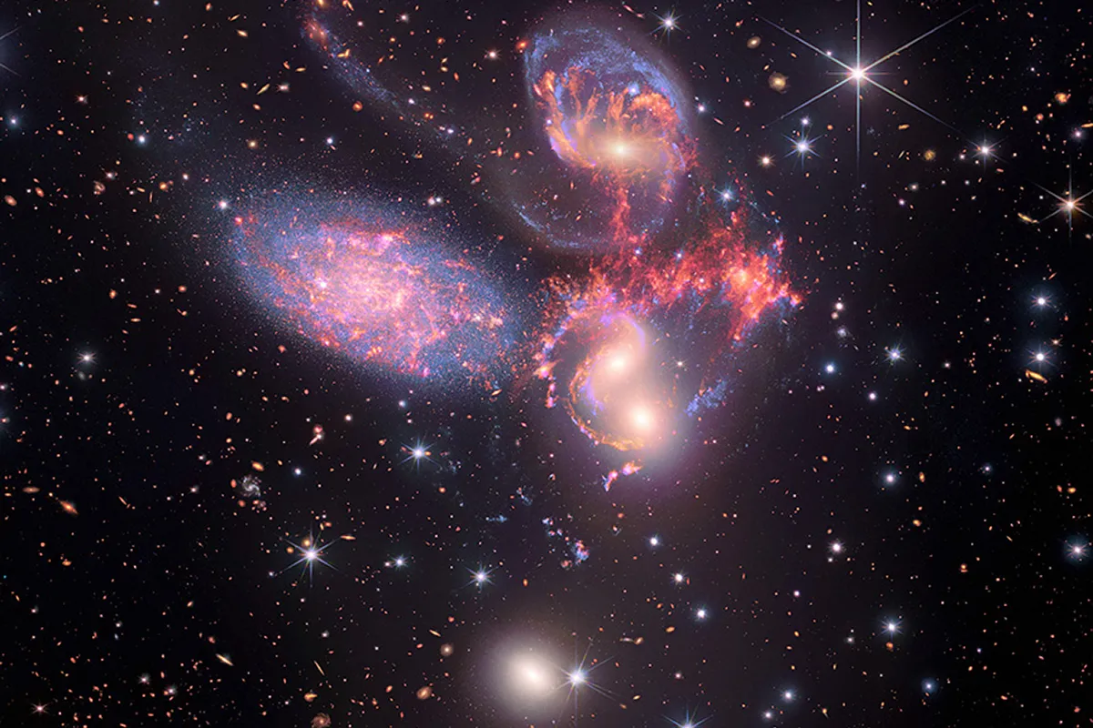 An image of Stephan's Quintet containing infrared light from the James Webb Space Telescope (red, orange, yellow, green, and blue) data from the Spitzer Space Telescope (red, green, and blue) and x-ray from Chandra (light blue). Credit: X-ray: NASA/CXC/SAO; IR (Spitzer): NASA/JPL-Caltech; IR (Webb): NASA/ESA/CSA/STScI; Sonification: NASA/CXC/SAO/K.Arcand, SYSTEM Sounds (M. Russo, A. Santaguida)