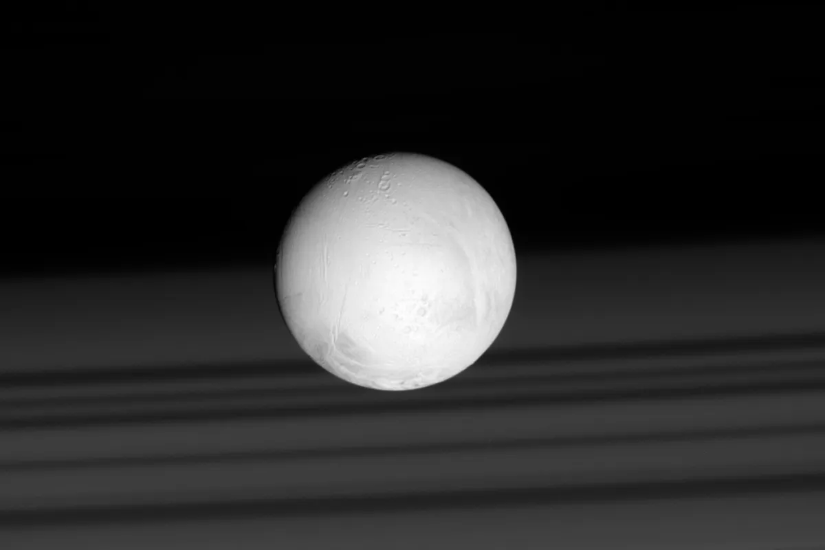 A view of Saturn's moon Enceladus captured by the Cassini spacecraft on 28 June 2007. In the background can be seen the shadows of Saturn’s rings, cast on the planet’s cloud tops. Credit: NASA/JPL-Caltech/Space Science Institute