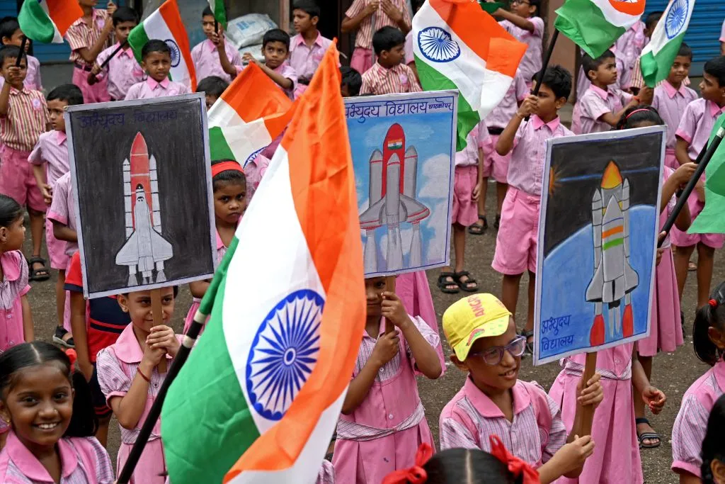 Students wave India's national flag as they hold posters in support of the Chandrayaan-3 spacecraft in Mumbai on 22 August 2023. Photo by INDRANIL MUKHERJEE/AFP via Getty Images