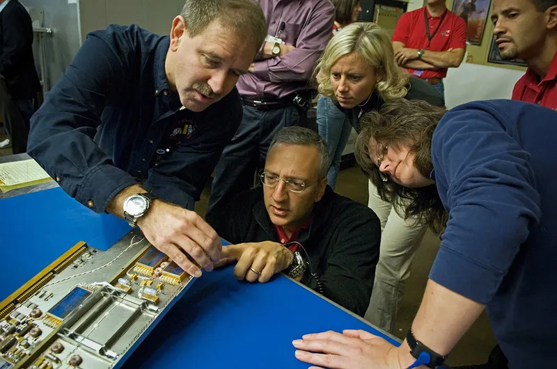 Astronauts John Grunsfeld (left) and Mike Massimino and a team of Hubble engineers inspect a circuit board prior to its instalment on the Hubble Space Telescope. Credit: NASA
