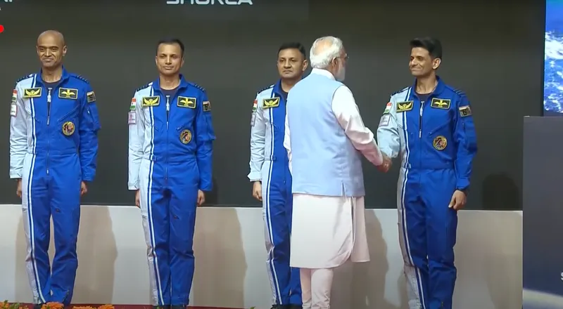 Four astronauts in blue jump suits. The president shakes hands with the last man on the right.