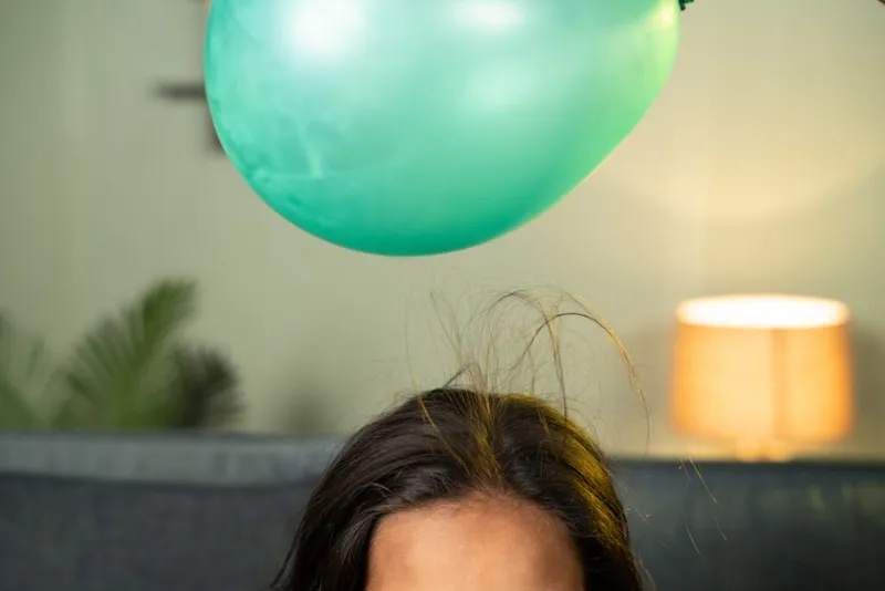 The balloon-hair trick illustrates how a charged object is surrounded by an electric field. Credit: lakshmiprasad S / Getty Images