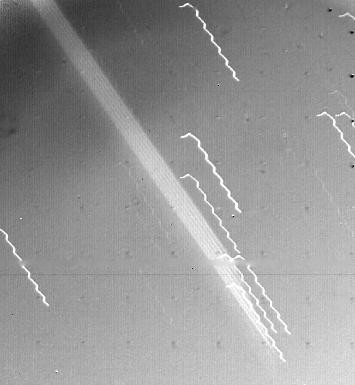 La amplia banda brillante que cruza diagonalmente el centro de esta imagen es la primera evidencia de los anillos de Júpiter, vista por la nave espacial Voyager 1 el 4 de marzo de 1979. El borde del anillo estaba a 1.212.000 km de la nave espacial y a 57.000 km de la nube visible. .  Puente de Júpiter.  Las líneas oscilantes son estrellas de fondo, cuyo aspecto se ve afectado por el movimiento de la nave espacial.  Crédito: NASA/JPL