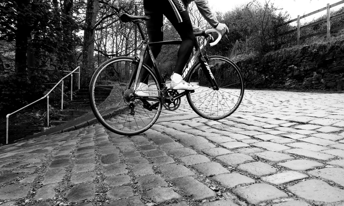 Black and white image of cyclist on teh cobbled Shibden Wall climb