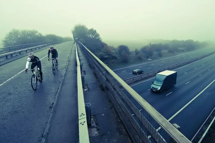 Two cyclists cross the M4 motorway on a bridge