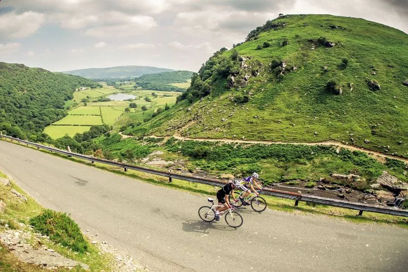 Two cyclists on a road climb in the Elan Valley near Rhayader, Wales