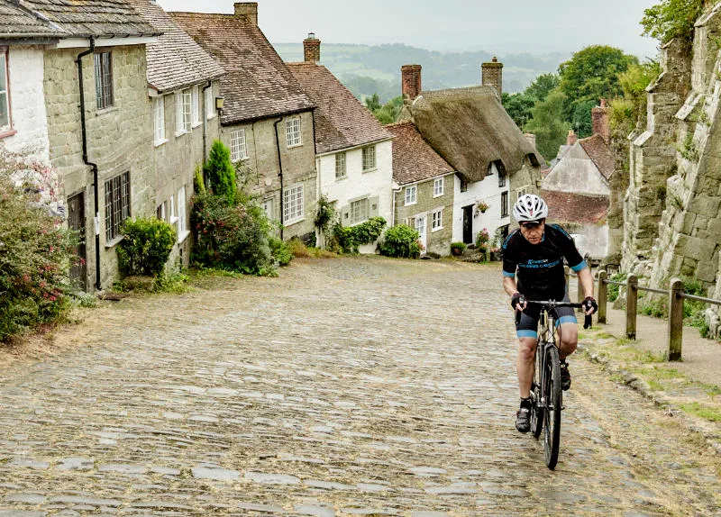Cyclist climbs Gold Hill, Shaftesbury, Dorset on Kinesis bike