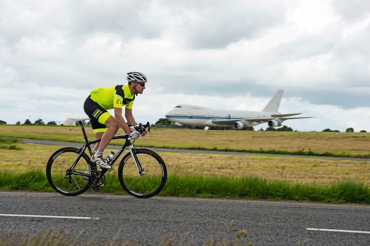 Cyclist riding past a Boeing 747 jumbo jet in Kent